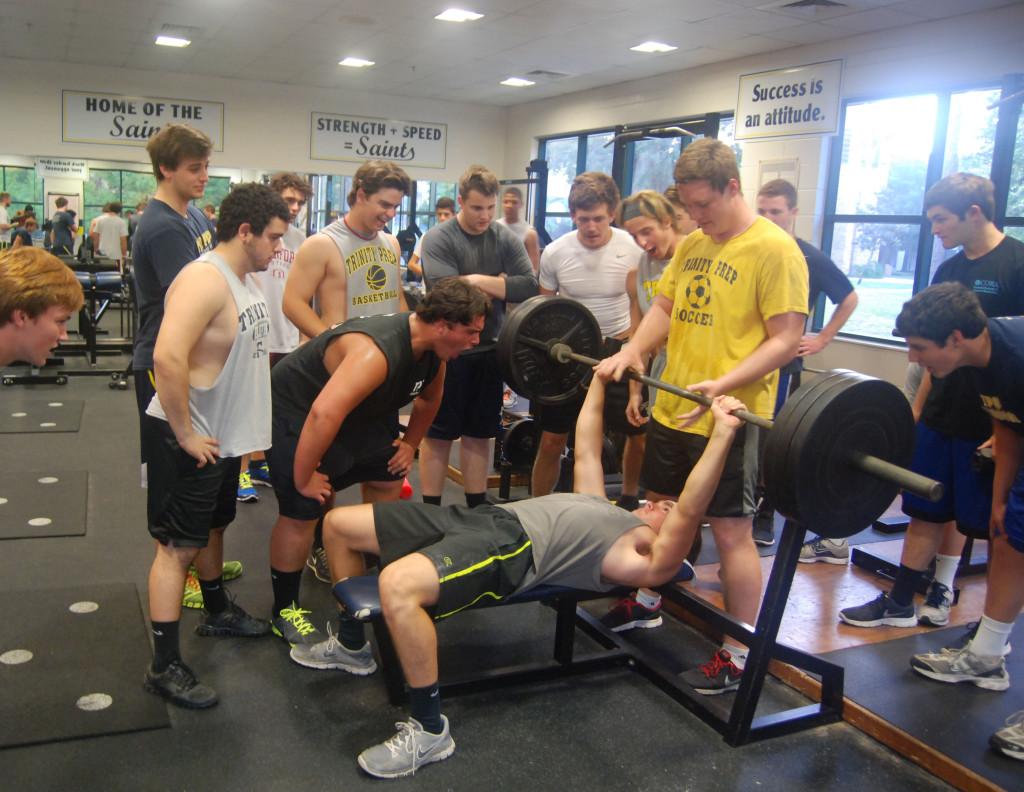 With consistent dedication to their sport, the football players push each other in the weight room during early morning workouts. 