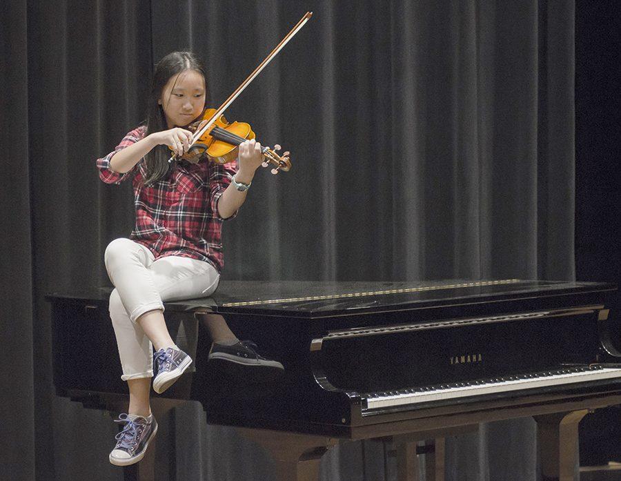 Maggie Yuan wielding her violin on top of her second favorite instrument, the piano.