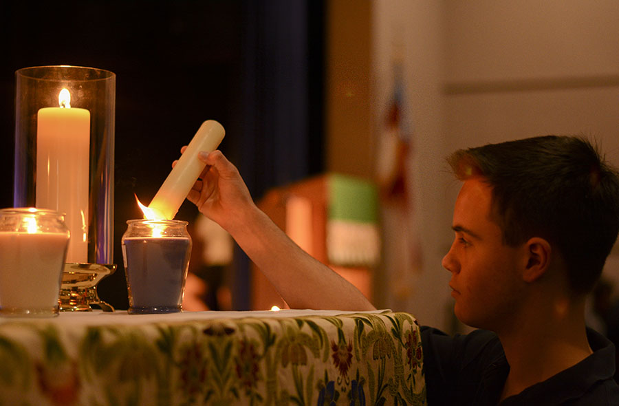 Junior Matthew Castro lights a candle for each human trafficking survivor story heard by the students during the Peace Jam chapel. There were six candles that were lit, representing the six survivors and their stories.