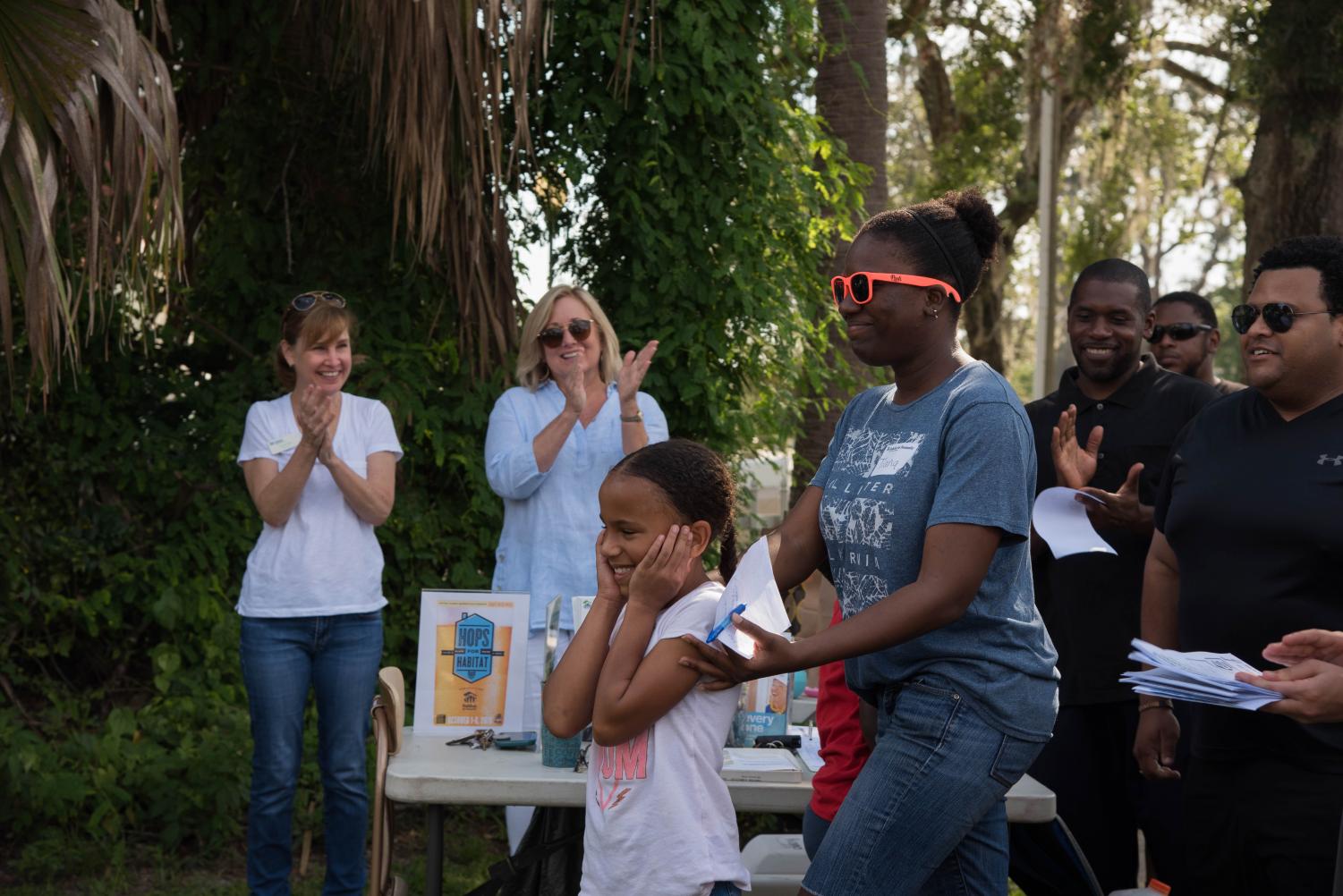 Tiana Thomas, Buchanan Maldonado and their daughter Kyle smile with excitement as their names are announced at the groundbreaking of Trinity's 20th Habitat house.