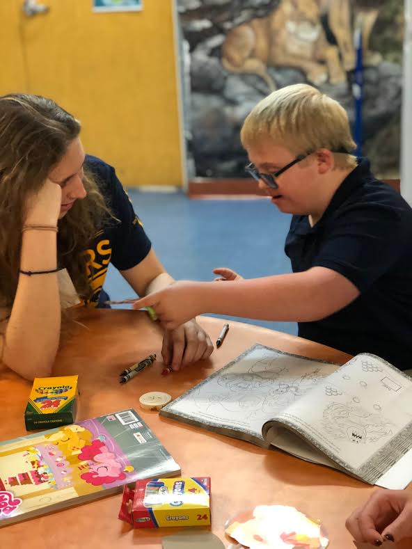 Senior Leah Mauer assists a student from UCP Bales in coloring. Mauer is one of twenty students who participates in Best Buddies.