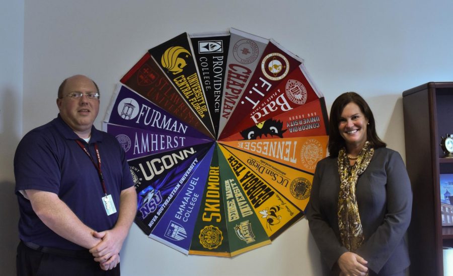 New college counselors, Russell Althouse and Christine Grover, pose by their college pennant wall in their office. 