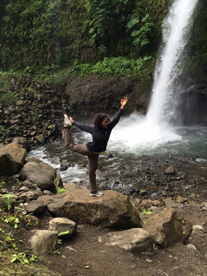 Omawale does yoga in front of a waterfall in Costa Rica on an international trip with students. 