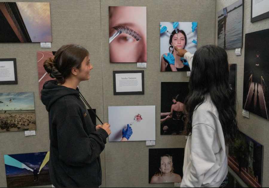Juniors Anna Miliotes and senior Anuha Tatineni, look at Tatinenis artwork displayed in the Rich Library. The seniors in AP photo have been preparing their photos all year to be presented to family and friends.