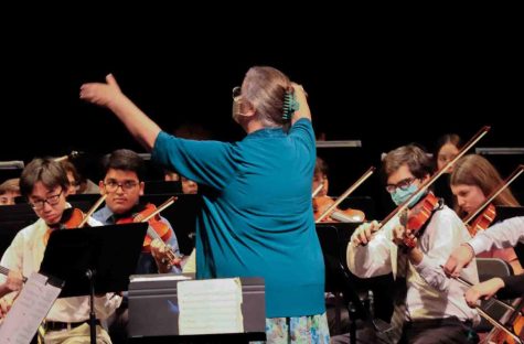 Fine arts teacher Maureen May conducts the orchestra during Easter Chapel. She has expanded the orchestra department since joining full-time in 2010.