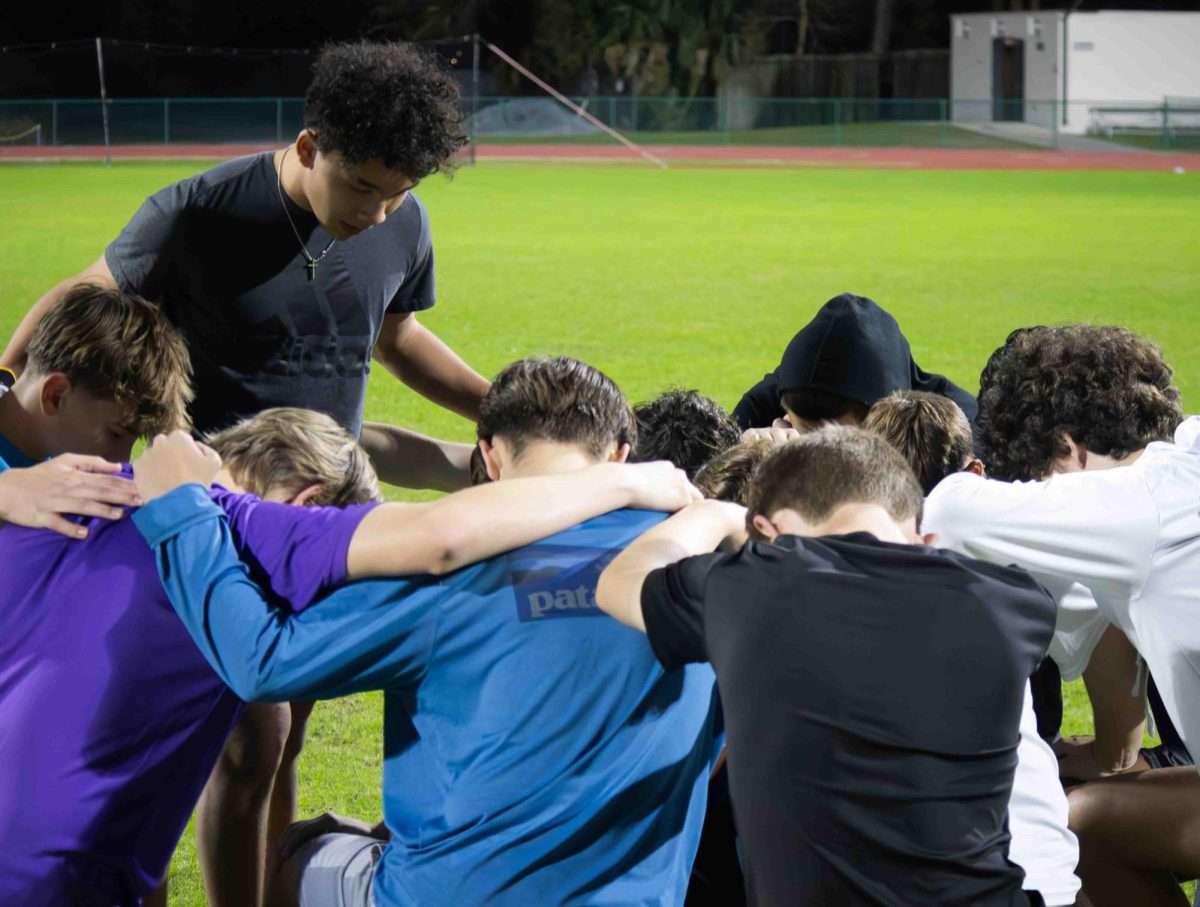 After a spring football practice, sophomore Orion Ratanasirintrawoot (standing) prays over his team.