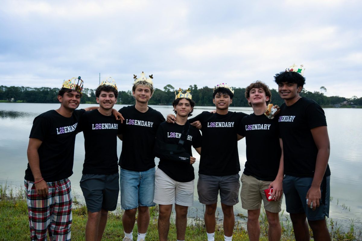 A group of senior boys show of their unique crowns in front of the lake.