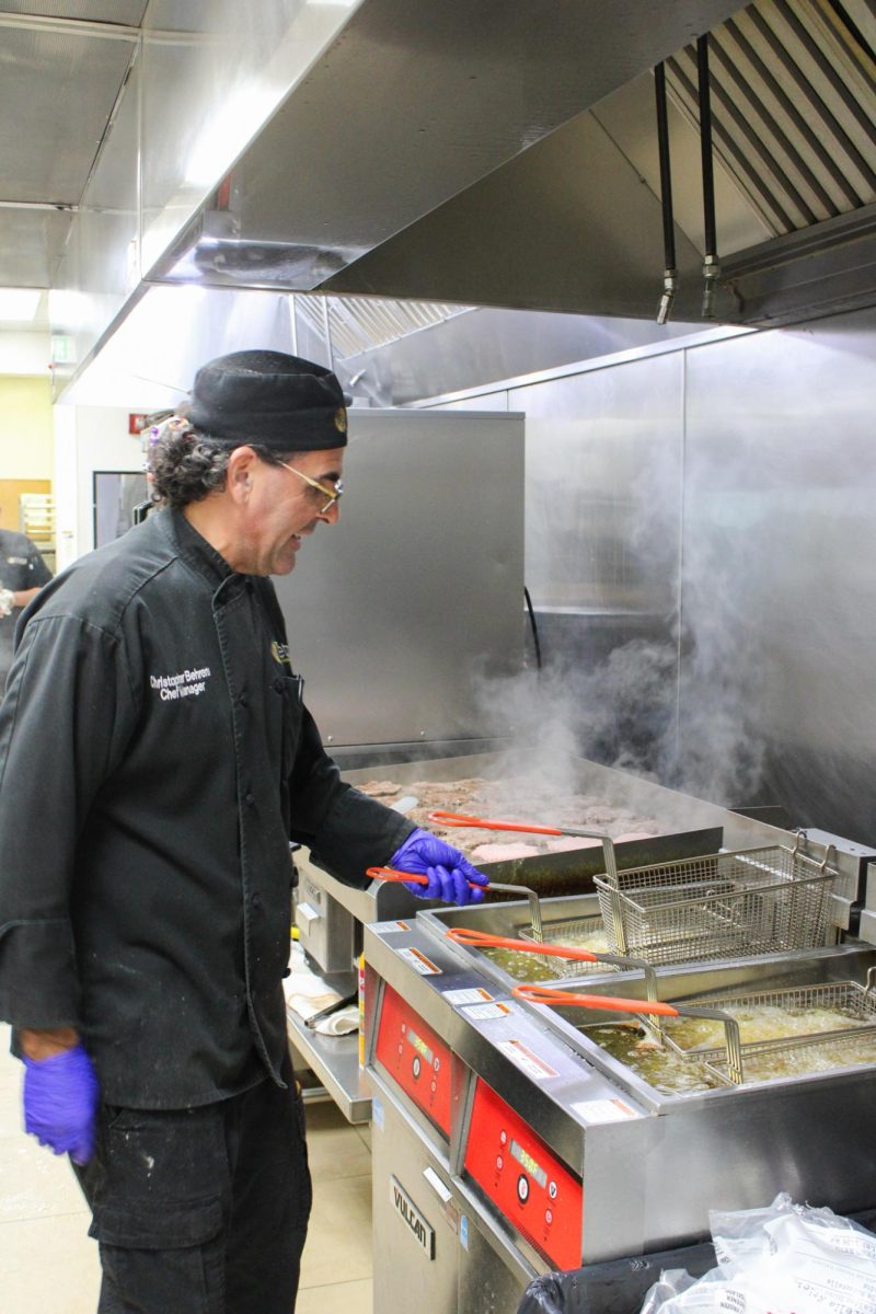 Food Director Chris Behrens prepares food in the grille, for around 400 students during lunch time. Many of those students have dietary restrictions.